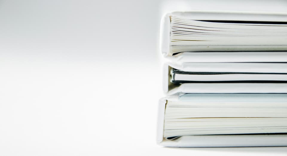 A stack of three white binders full of papers